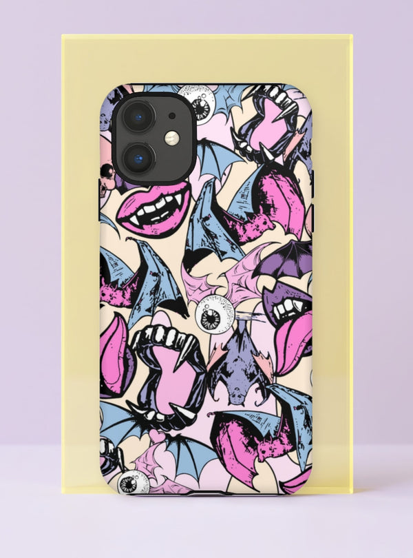 Front view of a dual layer tough phone case printed edge to edge with a pastel goth vampire collage. Open mouths with sharp fangs and pink tongues, staring bloodshot eyeballs, and blue and lavender bats with spread wings tumble over a cream background, drawn in bold black ink style lines with bubblegum pink, baby blue, and lilac fills. Creepy cute and fully unhinged. Spooky maximalist vampire bat phone accessory with open ports and camera cutout.