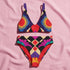 Two piece high waisted bikini in a bold 70s psychedelic geometric print. The sporty scoop top features bright yellow and red sunbursts over a black, purple, cream, and red colorblock background. The high cut bottoms carry matching geometric diamonds with hot pink and teal abstract palm leaves. Smooth form fitting recycled polyester fabric with UPF 50 sun protection and removable padding. Vibrant maximalist retro swimwear in saturated primary and secondary shades, made for pool parties, festivals, and loud s