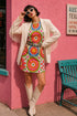 Short sleeve crew neck t-shirt dress on a cream background with an allover retro mod flower medallion print. Bold 60s daisies in red, yellow, and white sit at the center of concentric rainbow rings in lime green, hot pink, orange, and royal blue, with small magenta squares and tiny red checkerboard accents between the motifs. Above-the-knee straight fit silhouette in a 95 percent cotton, 5 percent elastane heavyweight stretch blend. Groovy retro flower power dress for dopamine dressing and easy summer outfi