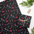 Christmas wrapping paper with a black background featuring colorful, stylized reindeer and Santa's sleigh designs. The reindeer and sleigh silhouettes are filled with skeletal patterns in shades of blue, pink, and red. Multicolored snowflakes in various sizes are scattered throughout. The paper has a whimsical, slightly gothic aesthetic that blends traditional holiday imagery with a unique, edgy twist.