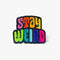 Colorful patch with the phrase 'Stay Weird' in vibrant, multicolored, textured letters, set against a black background. The design is playful and bold, celebrating uniqueness and individuality.