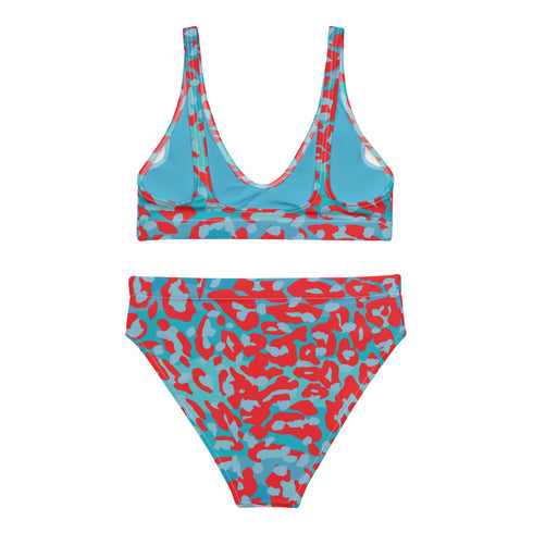 Vibrant two-piece leopard print swimsuit with abstract red and teal pattern. Sports bra-style top and high-waisted bottoms. Purple background. Tag visible. Trendy, colorful beachwear for modern style.