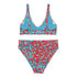 Vibrant two-piece leopard print swimsuit with abstract red and teal pattern. Sports bra-style top and high-waisted bottoms. Purple background. Tag visible. Trendy, colorful beachwear for modern style.
