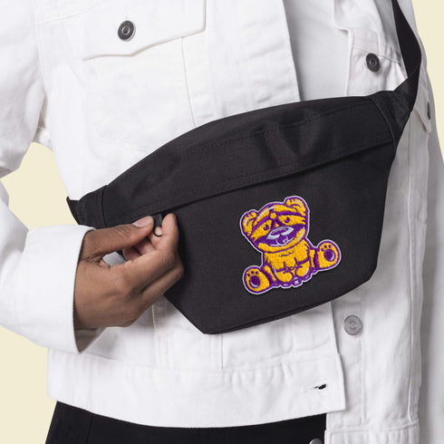 Patch featuring a cute bear in yellow and purple with a playful expression, wearing a BDSM harness and a ball gag. The design is fun and whimsical, combining bold colors with a cheeky style.