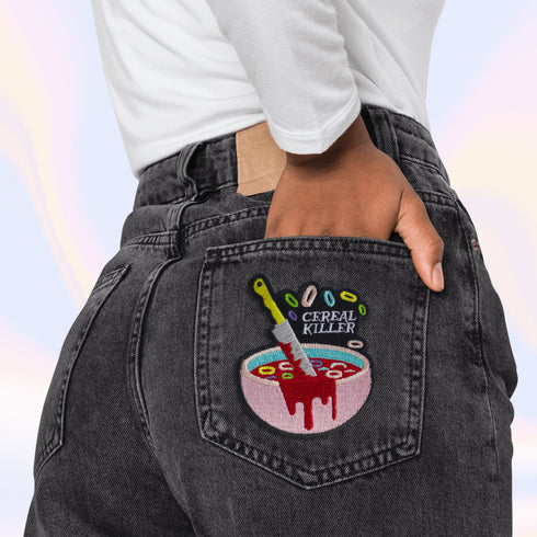 Patch featuring a bowl of cereal with a dripping knife and the text 'Cereal Killer,' set against a light pink background. The design combines playful cereal elements with a humorous, spooky twist.