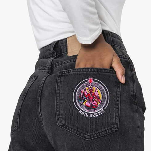 Patch featuring a red goat-headed figure with wings and a flaming torch, holding a pair of roller skates, surrounded by a circular design with the text 'Hail Skatin'. The design is bold and edgy, blending skate culture with a mystical motif.