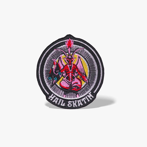 Patch featuring a red goat-headed figure with wings and a flaming torch, holding a pair of roller skates, surrounded by a circular design with the text 'Hail Skatin'. The design is bold and edgy, blending skate culture with a mystical motif.