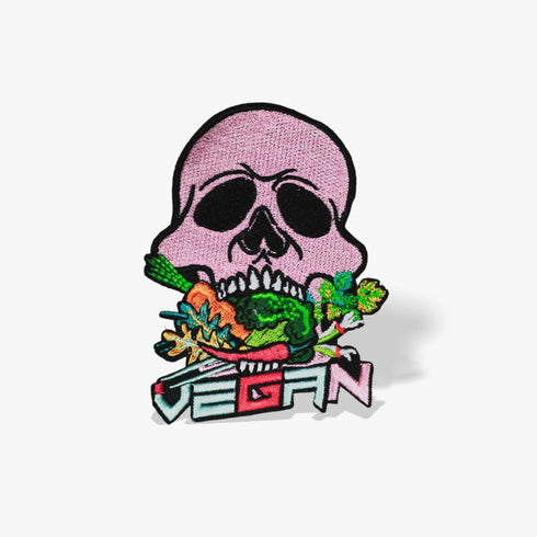 Patch featuring a pink skull biting into colorful vegetables with the word 'VEGAN' in bold letters below, set against a black background. The design is vibrant and edgy, blending vegan pride with a punk rock aesthetic.