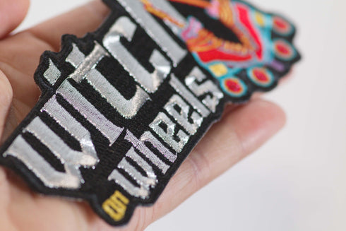 Patch with the text 'Witch on Wheels' featuring roller skates with witch's legs, set against a vibrant red background. The design combines playful witchcraft elements with a fun, retro skating theme.