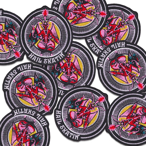 Patch featuring a red goat-headed figure with wings and a flaming torch, holding a pair of roller skates, surrounded by a circular design with the text 'Hail Skatin'. The design is bold and edgy, blending skate culture with a mystical motif.