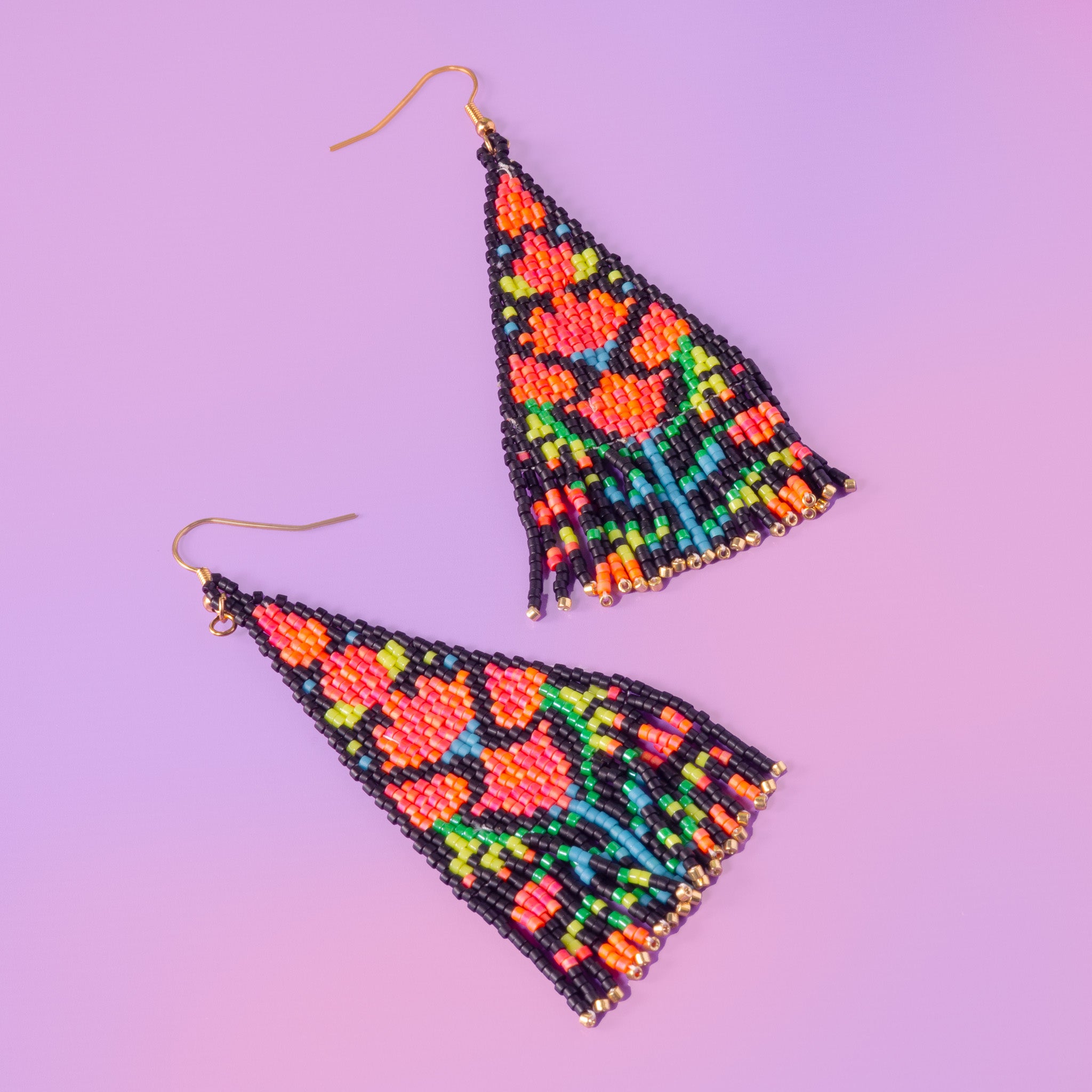 a pair of beaded triangle earrings on a purple background