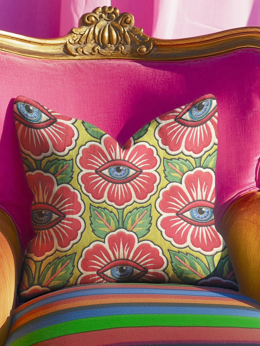 A square throw pillow cover featuring a repeating maximalist pattern. The background is a chartreuse yellow-green. Large stylized red floral blooms with green leaves fill the design. In the center of each red flower is a realistic blue human eye. The design is a flat print that mimics traditional tattoo art or faux crewel embroidery, creating a richly textured optical illusion on smooth fabric. The identical trippy floral pattern repeats on the front and back of the standalone case.