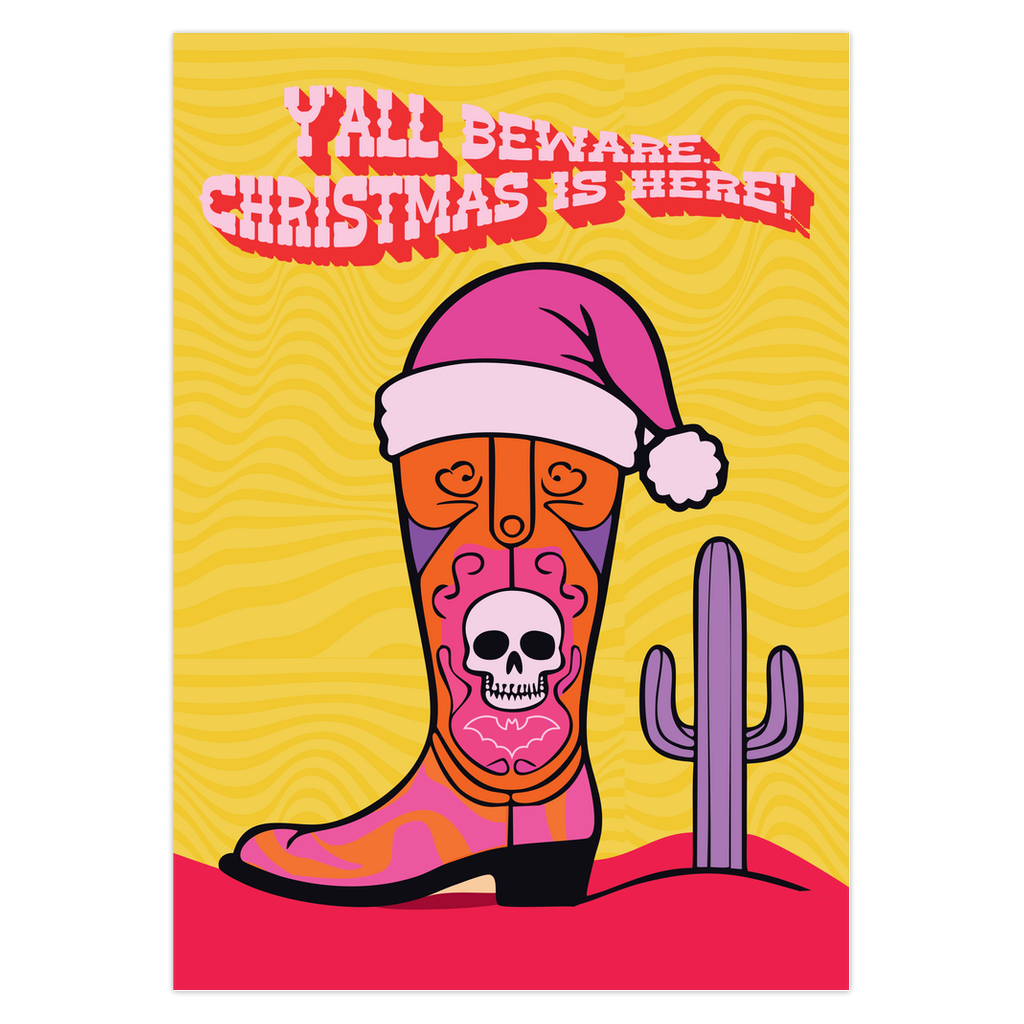 Colorful Christmas card with a yellow background. Features a stylized cowboy boot decorated with a skull, hearts, and swirls in pink, orange, and purple. The boot wears a pink Santa hat. A green cactus stands beside the boot. Top text reads 'Y'ALL BEWARE, CHRISTMAS IS HERE!' in red, wavy letters. Card has a purple border. Inside message: 'May Your days be merry, bright and full of southern delight.' The design blends Christmas, Western, and Day of the Dead motifs for a unique, playful holiday greeting