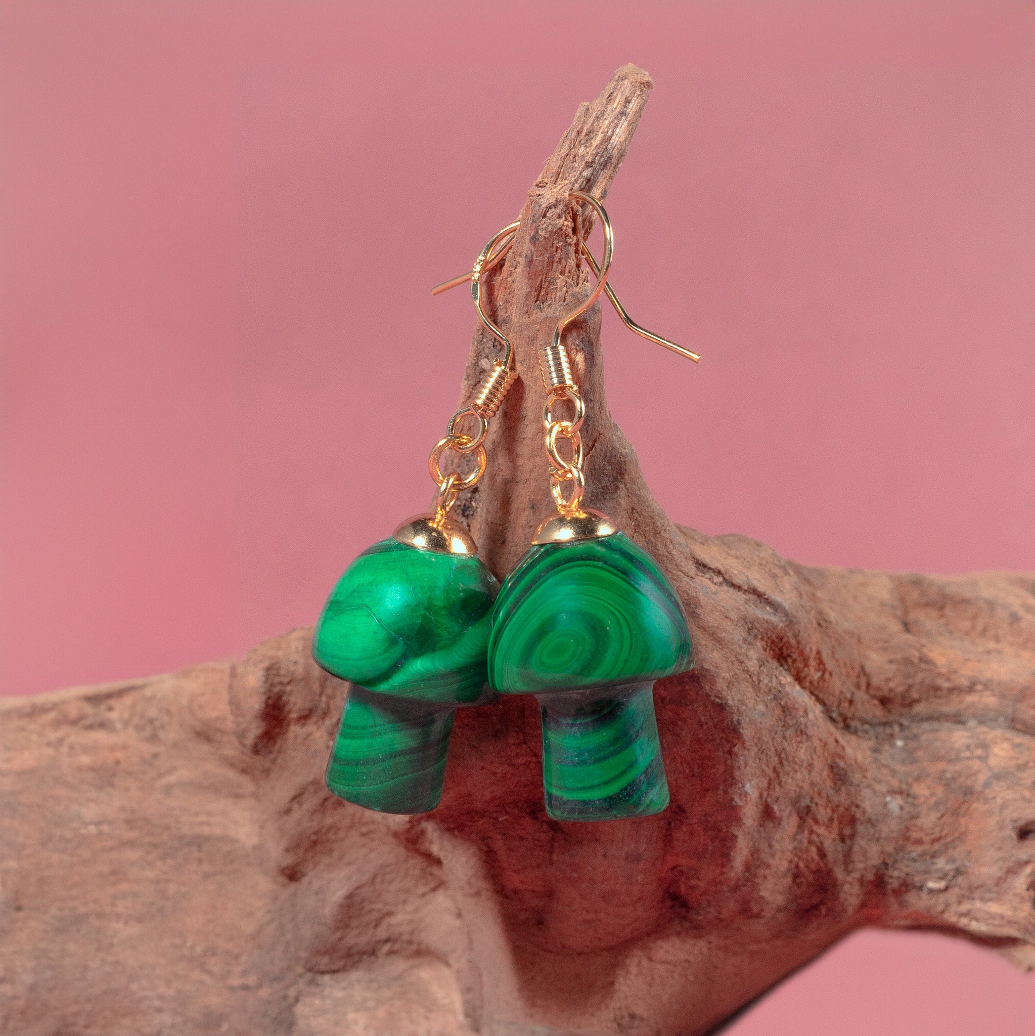 a pair of green earrings hanging from a tree branch
