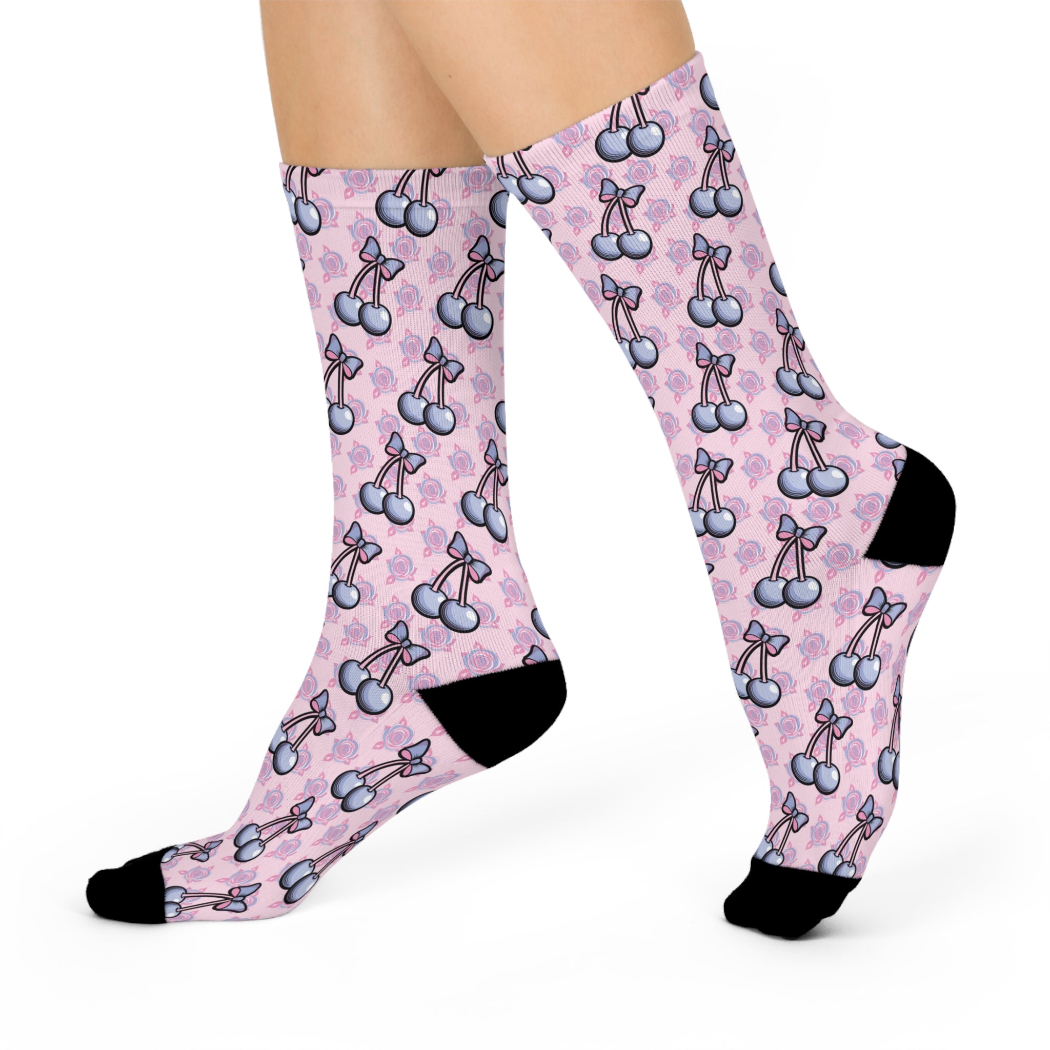 Pink crew socks with playful cherry and bow print. Retro-inspired design with a coquette aesthetic against a soft pink background. Black heel and toe accents.