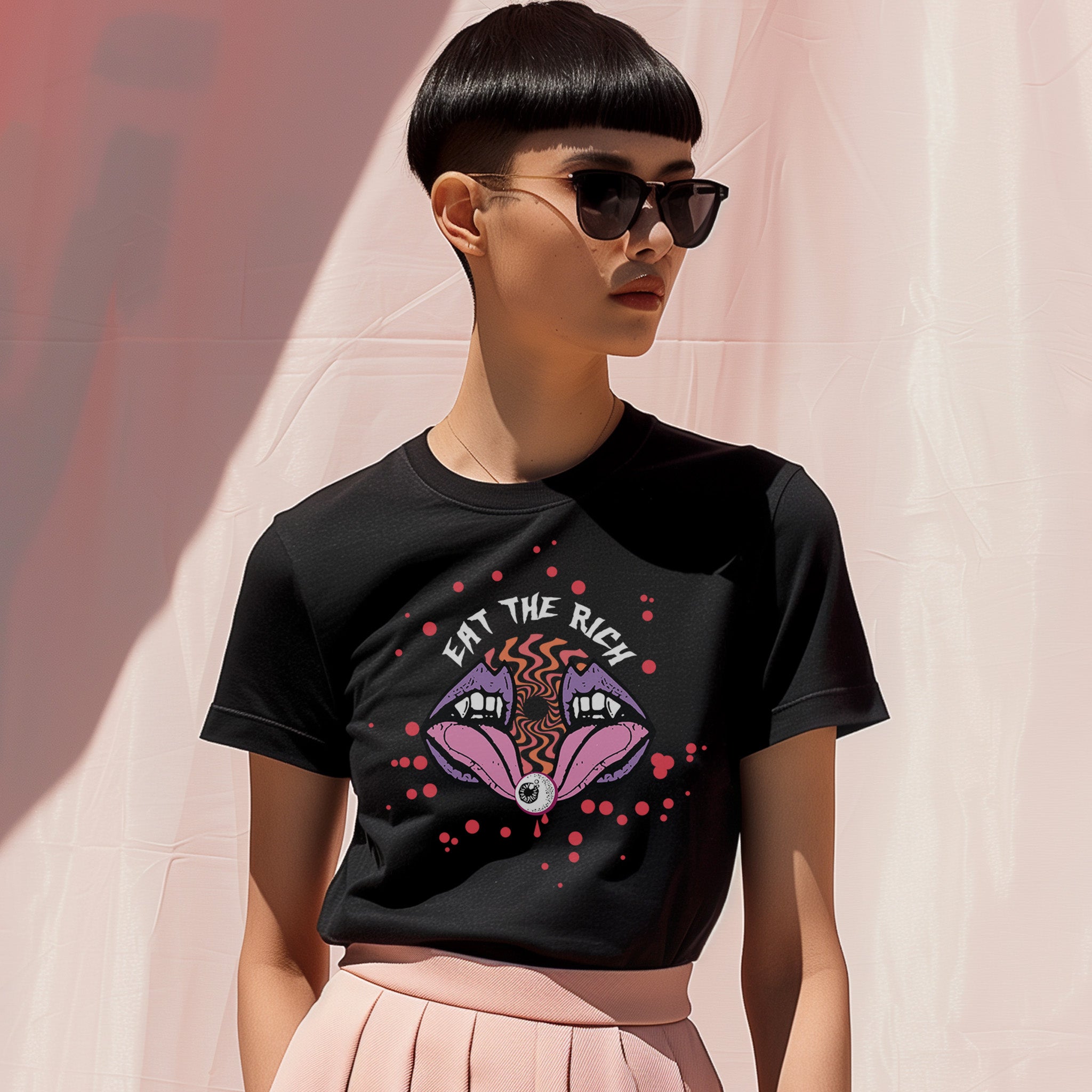T-shirt featuring a surreal, psychedelic design centered on the chest. An open mouth with sharp vampire-like teeth and pink tongue dominates the image. Between the teeth, a hypnotic swirling pattern in rainbow colors leads to a single eyeball on the tongue. 