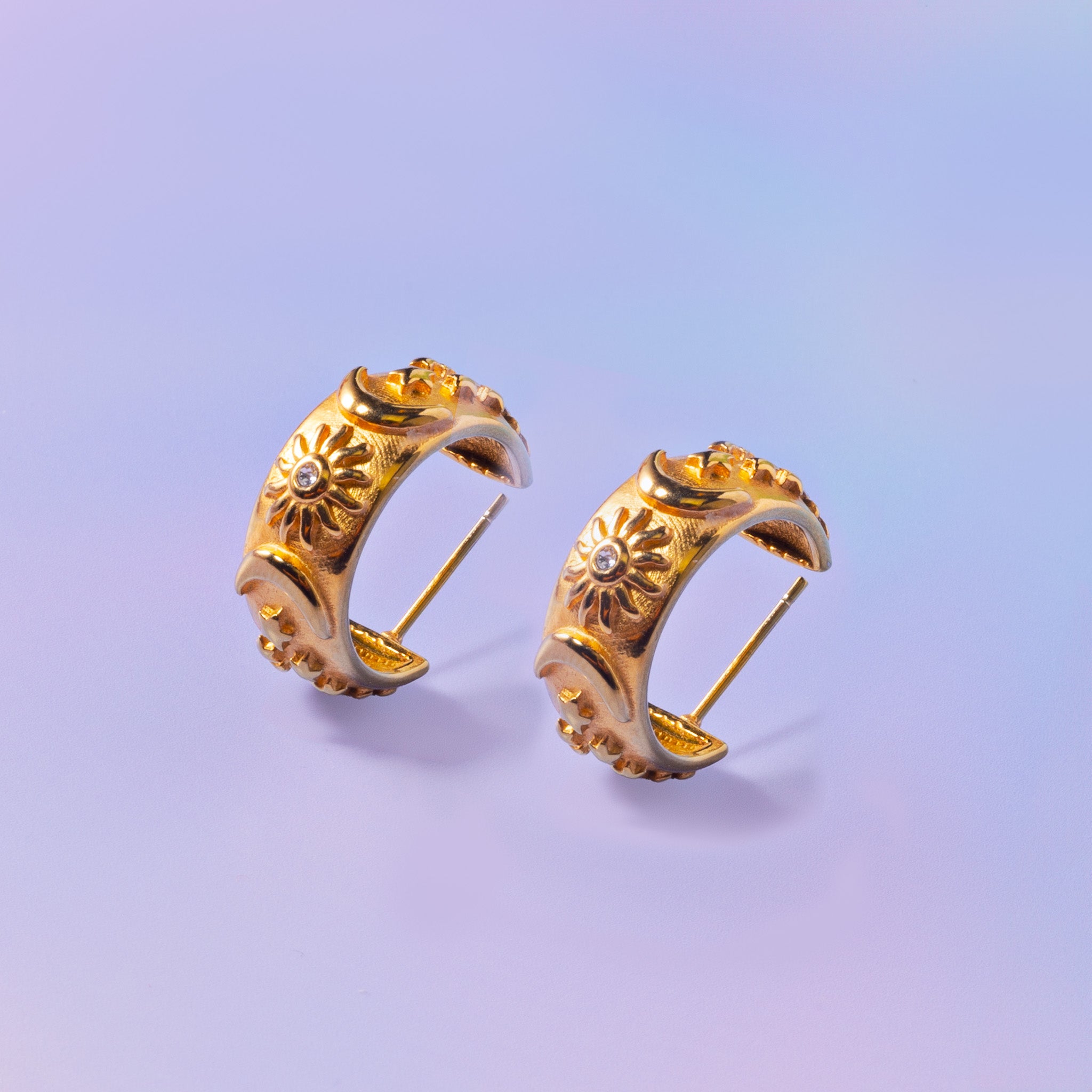 a pair of gold earrings on a blue background