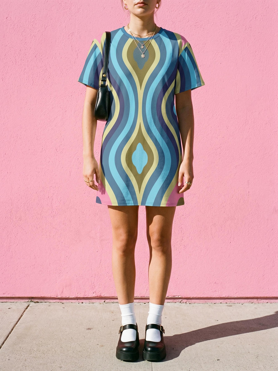 Short sleeve crew neck t-shirt dress in a relaxed, oversized straight cut, made of 100% polyester with a soft matte finish. An edge-to-edge all-over print shows rippling op-art vertical wave curves in sky blue, steel blue, navy, olive green, and pale chartreuse, with hot pink and red accents at the hem and shoulders. Psychedelic 70s retro, optical illusion, trippy groovy maximalist alt fashion for festivals.